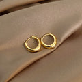 Gold hoop earrings on a beige fabric surface