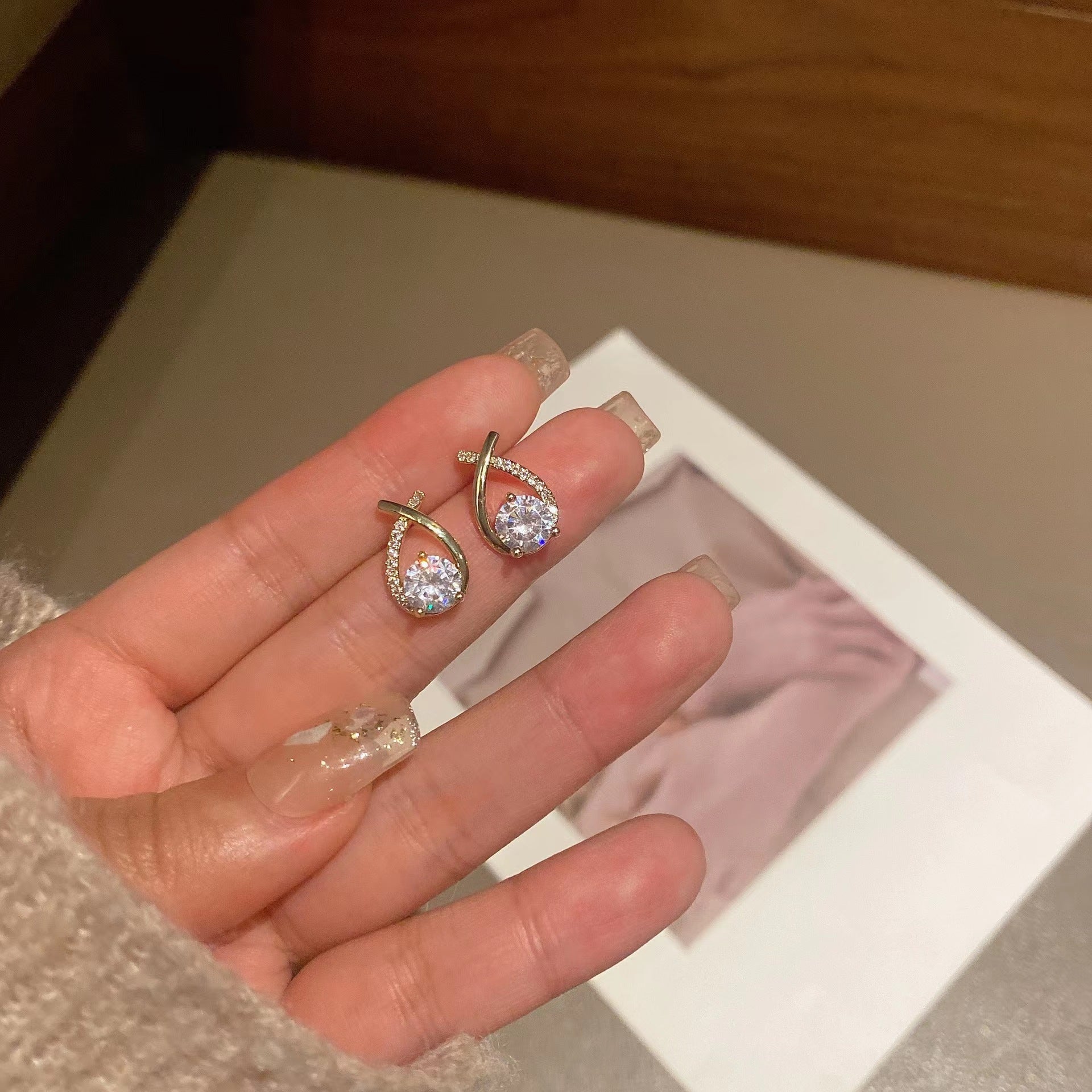 Hand holding a pair of diamond earrings with a blurred background