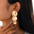 Close-up of a woman wearing gold earrings with a blurred background