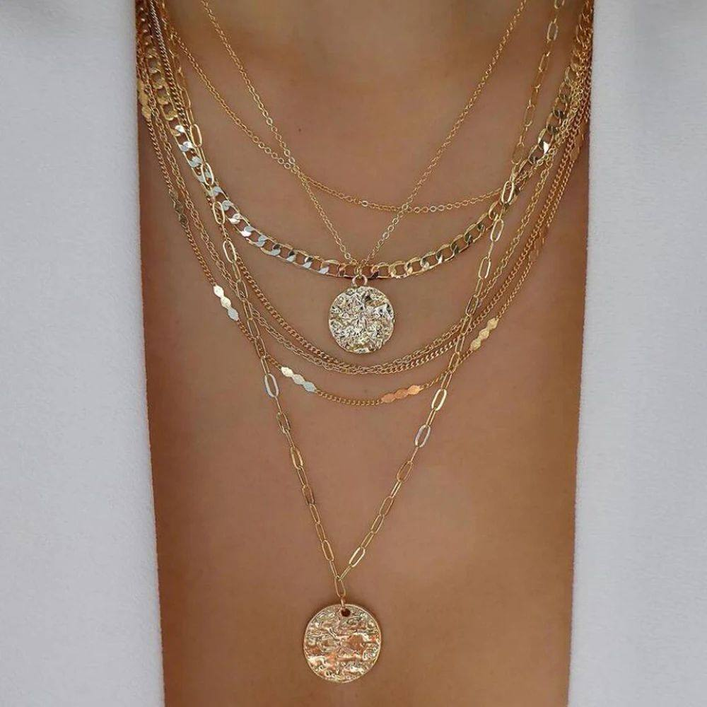 Multiple gold necklaces with circular pendants on a white background
