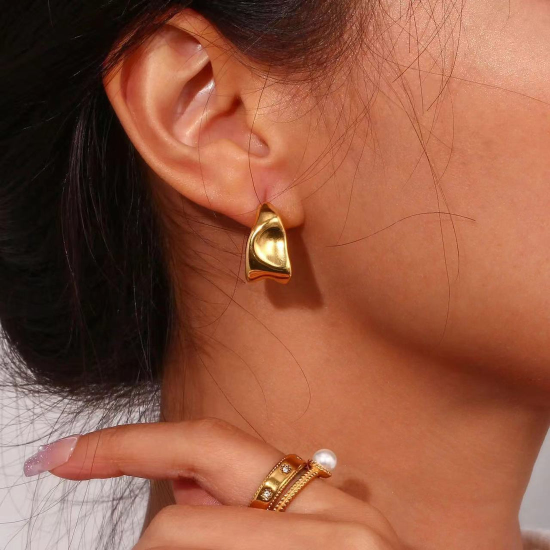 Gold earring worn by a person with a blurred background