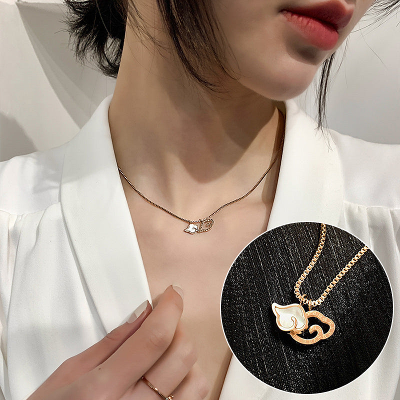 Person wearing a gold necklace with a cat pendant, close-up on neck and hand.