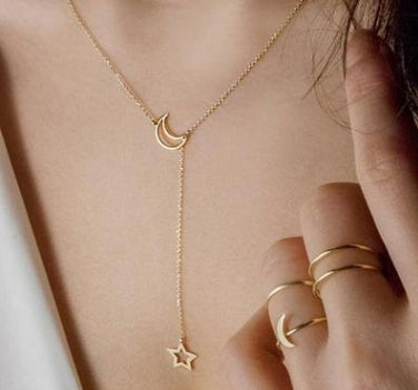Gold necklace with a moon and star pendant worn by a person.