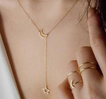 Gold necklace with a moon and star pendant worn by a person.