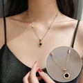 Rose gold necklace with black pendant worn by a person, close-up view.