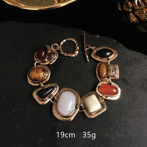 Bracelet with stone beads on a dark surface, showing measurements.