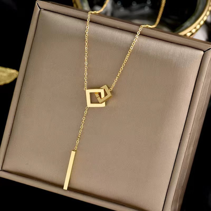 Gold necklace with geometric pendants on a brown jewelry box
