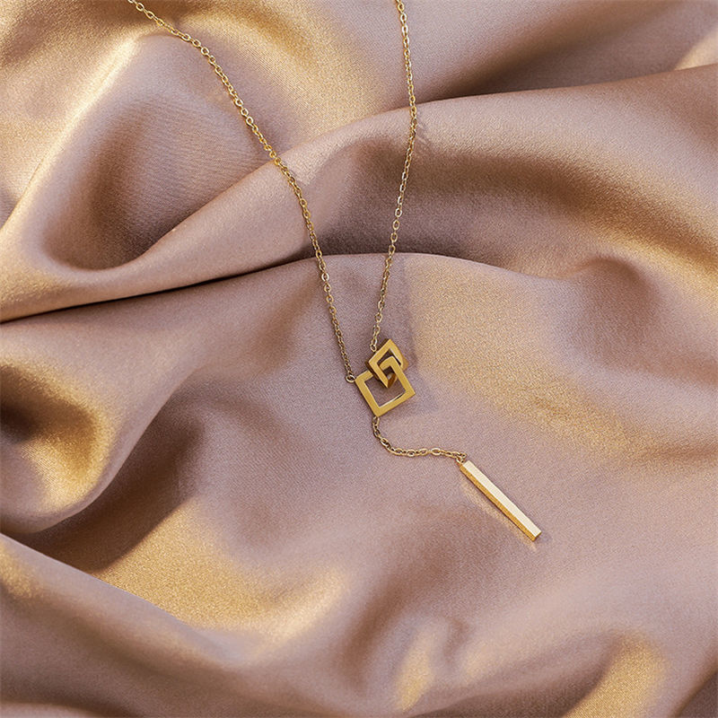 Gold necklace with geometric design on a beige fabric background