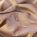 Rose gold necklace with geometric pendants on a beige fabric background