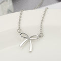 Silver bow-shaped necklace on a white surface