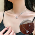 Silver butterfly necklace worn by a person, with an inset showing a close-up of the necklace on a wooden surface.