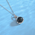 Pearl necklace with a black pearl on a blue background
