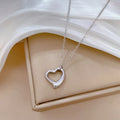 Silver heart-shaped necklace on a beige surface with white fabric