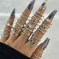 Hand wearing multiple silver rings with various designs on a neutral background