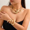 Woman wearing a gold necklace and bracelet on a neutral background