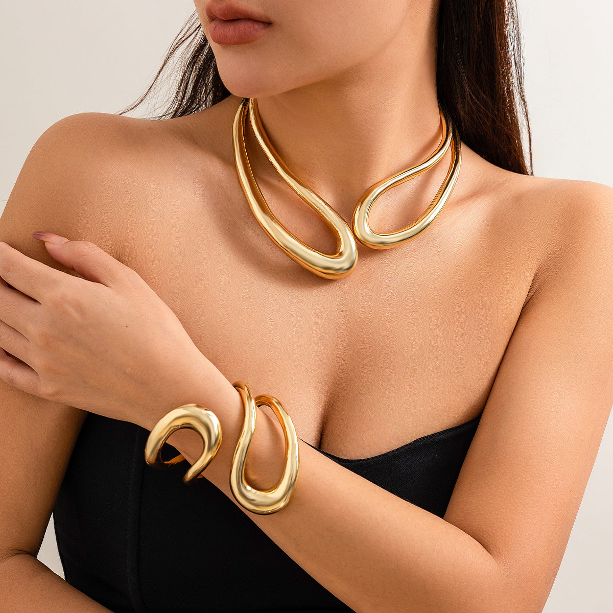 Woman wearing a gold necklace and bracelet on a neutral background