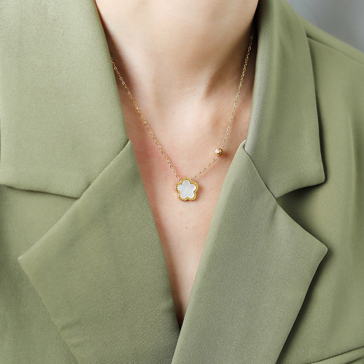 Necklace with a star-shaped pendant worn by a person in a green outfit.