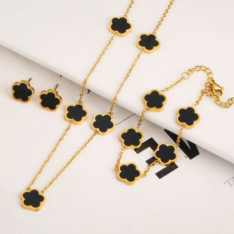 Gold necklace with black clover-shaped pendants on a white background