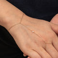 Rose gold anklet on a person's ankle against a dark background