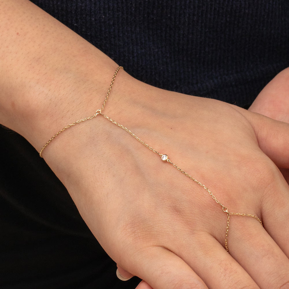 Rose gold anklet on a person's ankle against a dark background