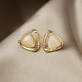 Gold earrings with white stones on a beige fabric background