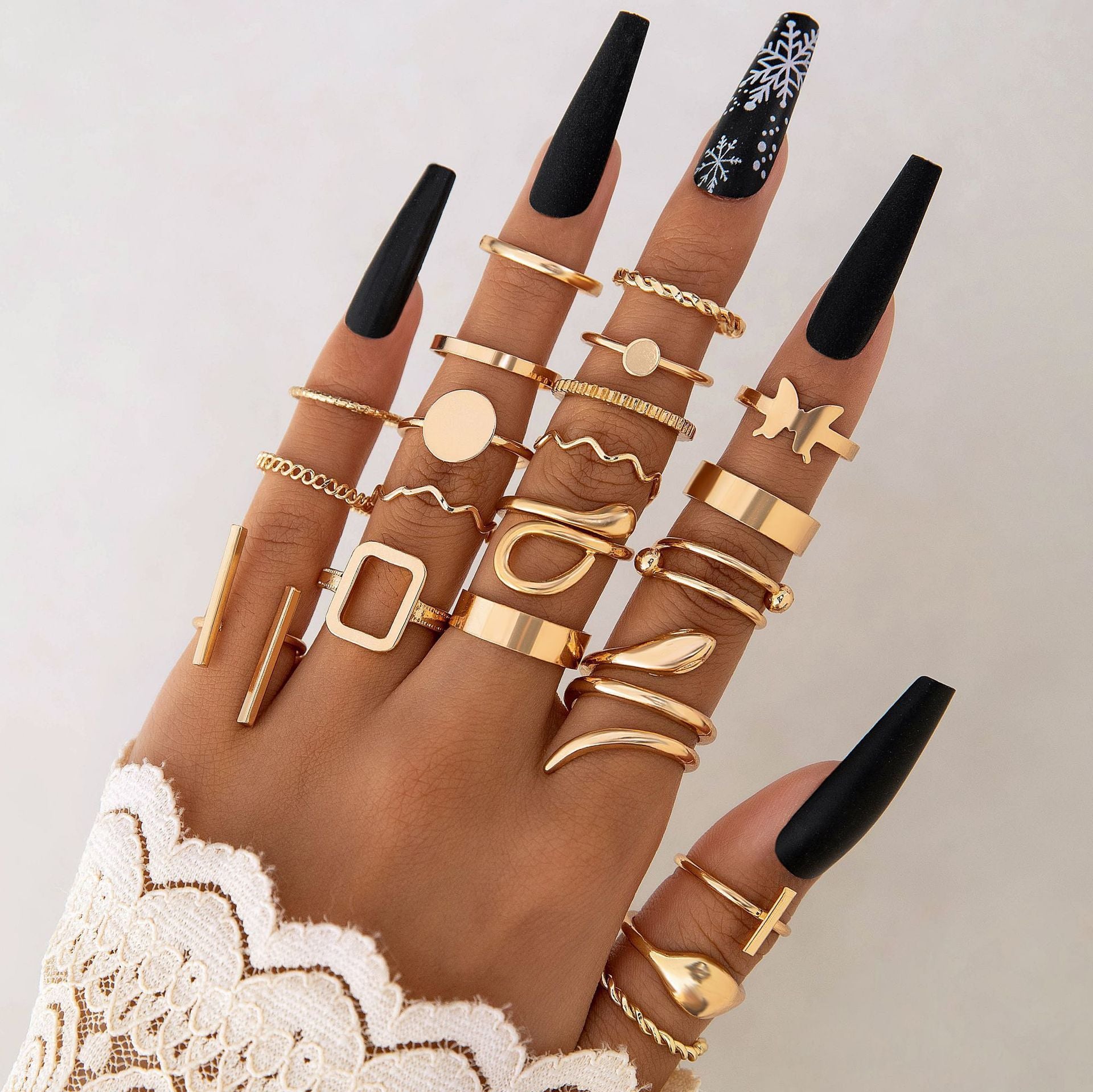 Hand wearing multiple gold rings on a plain background