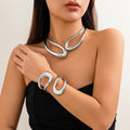Woman wearing a silver necklace and bracelet on a plain background