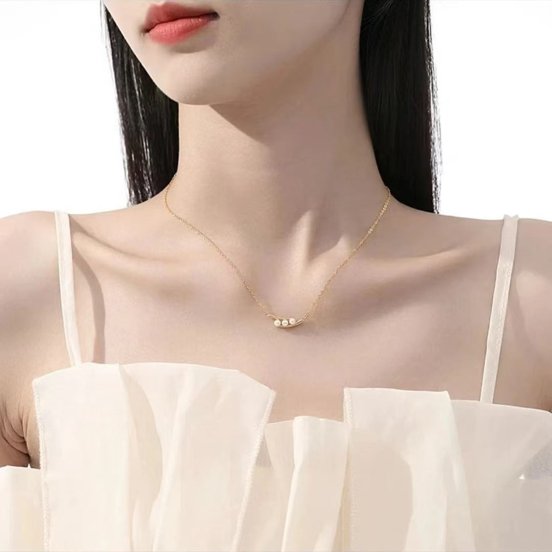 Woman wearing a delicate gold necklace with small beads against a white background