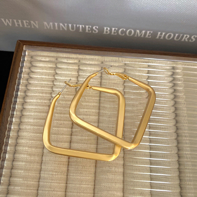 Gold hoop earrings on a textured surface with a book in the background.