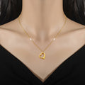 Gold heart-shaped necklace on a mannequin with a black background