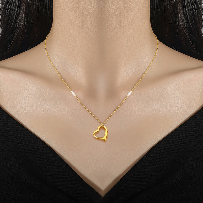 Gold heart-shaped necklace on a mannequin with a black background