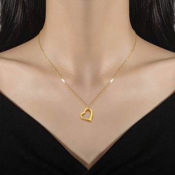 Gold heart-shaped necklace on a mannequin with a black background