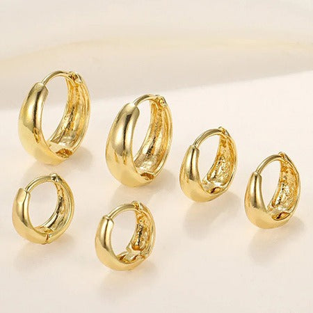 Set of gold hoop earrings on a light background