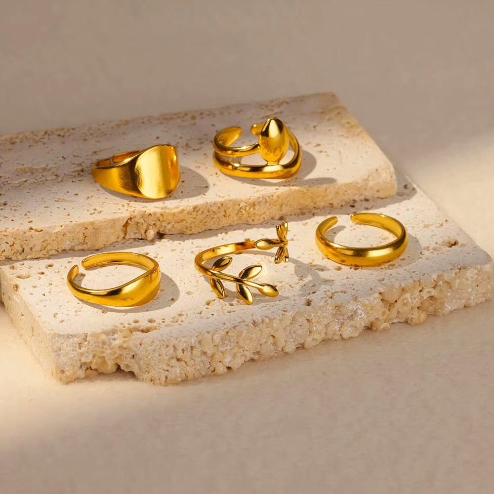 Set of gold rings on a textured stone surface