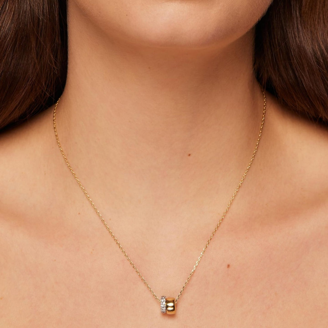 Gold necklace with a small pendant on a person's neck