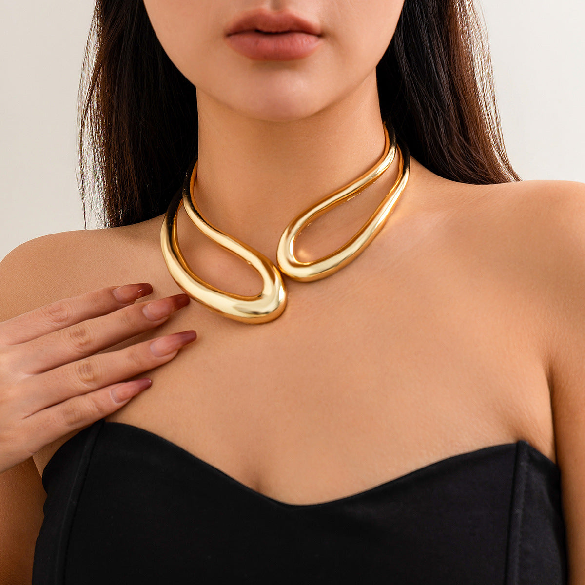 Woman wearing a gold necklace with a plain background