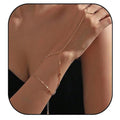 Rose gold body chain worn on a person's arm against a neutral background