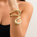Gold bracelet on a person's wrist against a neutral background