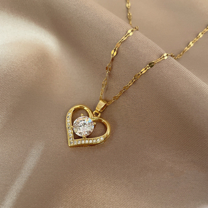 Gold heart-shaped necklace with a clear gemstone in a beige jewelry box.