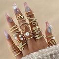 Hand wearing multiple gold rings with various designs on a beige background