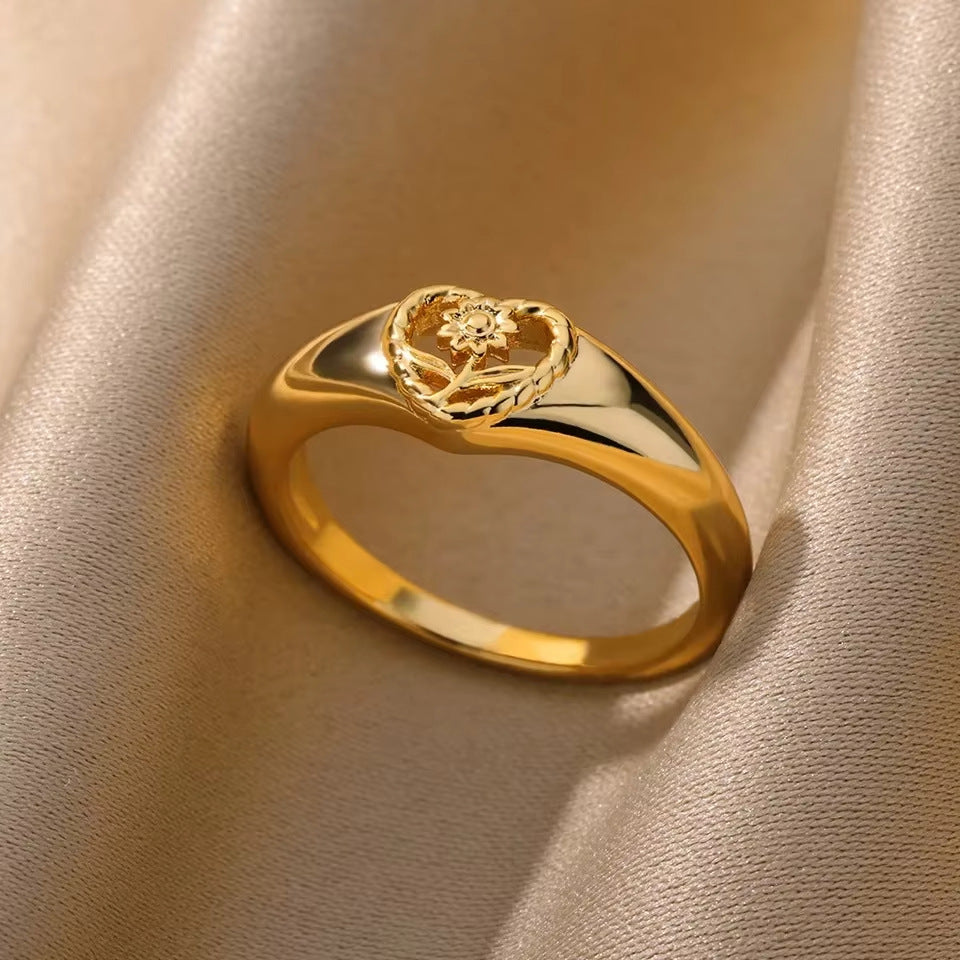 Gold ring with floral design on a beige fabric background