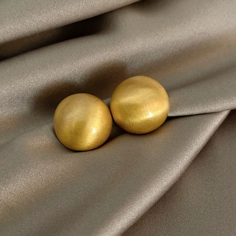 Collection of gold earrings on a beige fabric background