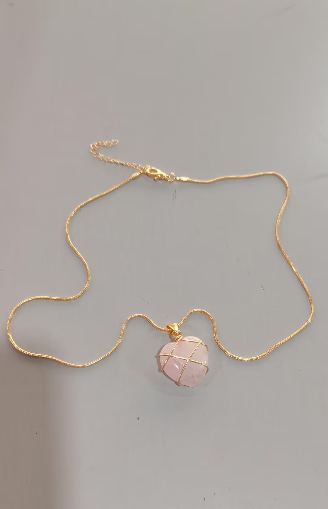 Necklace with a pink stone pendant on a gray background