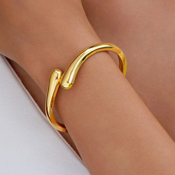 Gold bracelet on a person's wrist with a neutral background