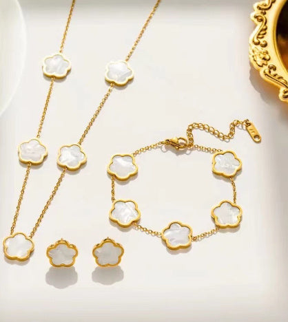 Gold necklace with white floral pendants on a light background