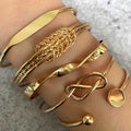 Gold bracelets on a person's wrist against a neutral background