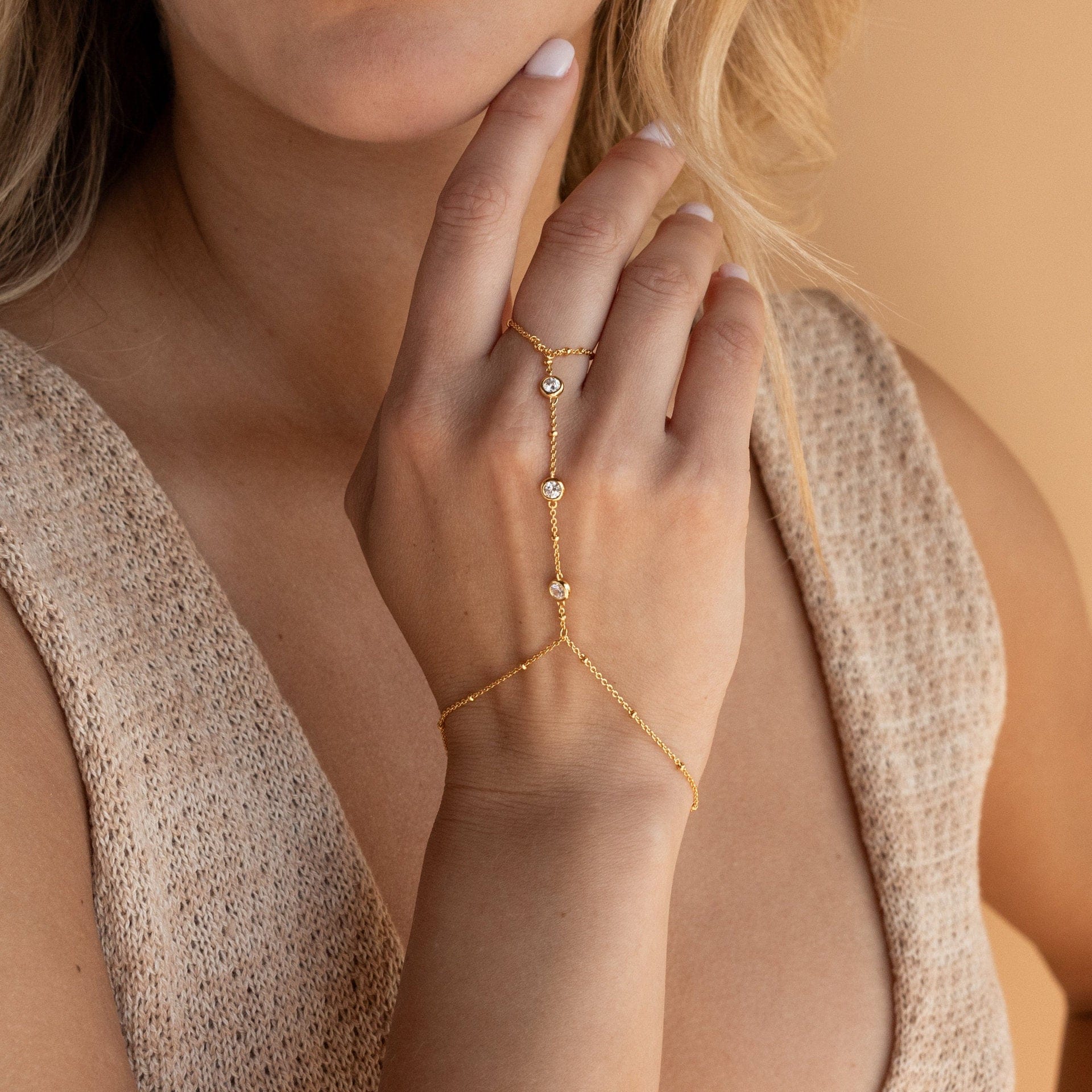 Gold ring with small stones on a hand against a neutral background
