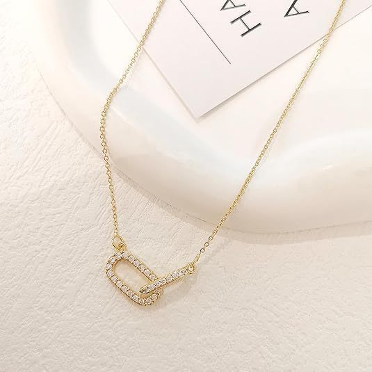 Gold necklace with a heart-shaped pendant on a light background