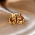 Pair of gold hoop earrings on a beige fabric background