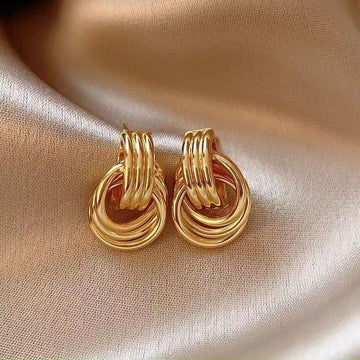 Pair of gold hoop earrings on a beige fabric background